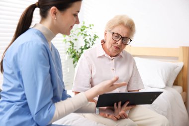 İçeride yaşlı bir kadını muayene eden bir hemşire. Ev sağlık hizmetleri