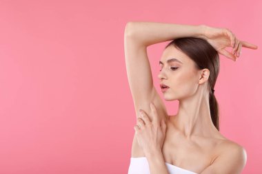 Pembe arkaplandaki epilasyondan sonra pürüzsüz cilt gösteren genç kadın, metin için boşluk