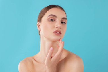 Açık mavi arka planda büyüleyici genç bir kadının portresi.