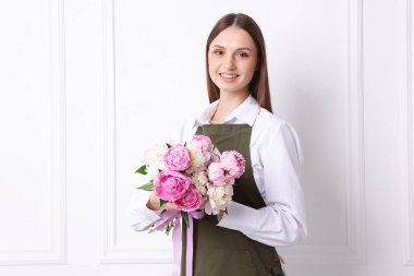 Beyaz duvarın yanında güzel şakayık demeti olan bir çiçekçi.