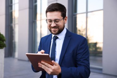 Ofis binası yakınında tabletle başarılı bir iş adamı