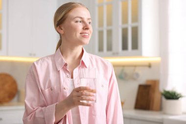 Mutfakta bir bardak suyu olan genç bir kadın.