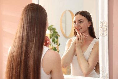 Güzel bir kadın aynada kendine bakıyor.