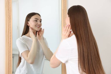 Güzel bir kadın aynada kendine bakıyor.