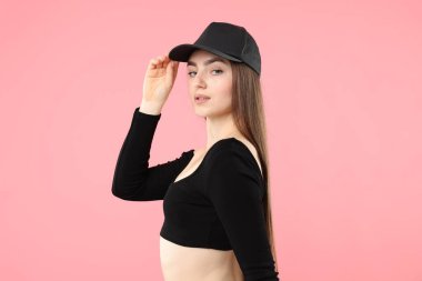 Pembe arka planda şık beyzbol şapkalı güzel bir kadının portresi.