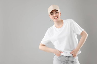 Gri arka planda şık beyzbol şapkalı gülümseyen kadın portresi. Metin için boşluk