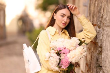 Şehir caddesinde elinde şakayık demeti olan bir kadın