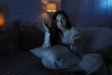 Evde uykusuzluk çeken, yastıklı, hayal kırıklığına uğramış bir kadın. Mesaj atmak için yer var.