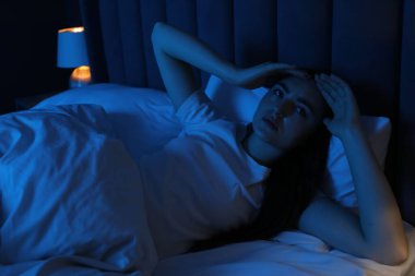 Evde yatakta uykusuzluk çeken hayal kırıklığına uğramış bir kadın.