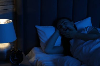 Evde yatakta uykusuzluk çeken hayal kırıklığına uğramış bir kadın.