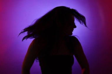 Renkli arka planda neon ışıklarla poz veren kadın silueti