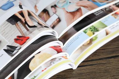 Ahşap masada farklı açık dergiler var.