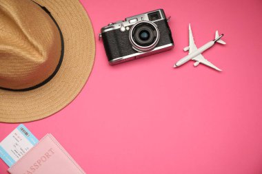 Uçak modeli, pasaport, uçuş bileti, eski fotoğraf makinesi ve pembe arka planda şapka, düz konum. Metin için boşluk