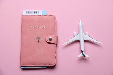 Uçak modeli, uçuş bileti ve pembe arka planda pasaport.
