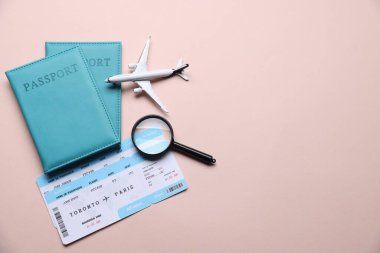 Uçak modeli, pasaportlar, uçuş biletleri ve bej arka planda büyüteç, düz konum. Metin için boşluk