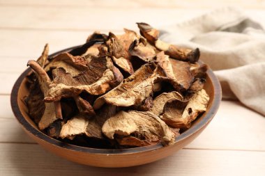 Kurumuş mantar parçaları açık tahta masada kasede, yakın plan.