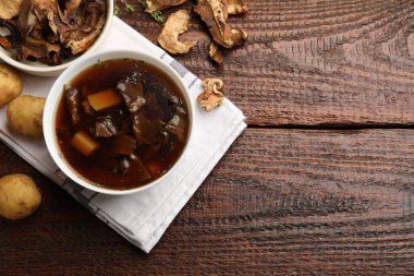 Tabakta lezzetli çorba, çiğ patates ve ahşap masada kuru mantar. Metin için boşluk