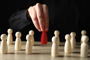 Dağılabilirsiniz. Masadaki ahşap figürler arasından kırmızı figürü seçen kadın, yakın plan.