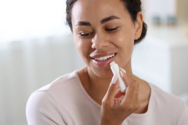 Gülümseyen kadın dudaklarına merhem sürüyor arka planda bulanık, yakın plan