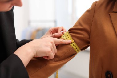 Atölyedeki kadına terzi ceketi giydirme kolu, yakın plan.