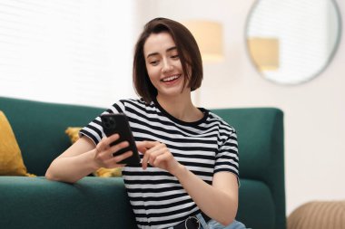 Evde modern akıllı telefon kullanan güzel bir kadın.