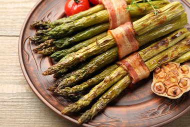 Ahşap masada domuz pastırması ile servis edilen lezzetli kuşkonmaz, yakın plan.