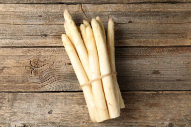 Ahşap masanın üstünde çiğ beyaz kuşkonmaz mızrakları.