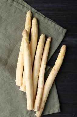 Çiğ beyaz kuşkonmaz mızrakları siyah ahşap masada, düz yatıyordu.