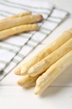 Beyaz ahşap masada çiğ kuşkonmaz mızrakları, yakın plan.