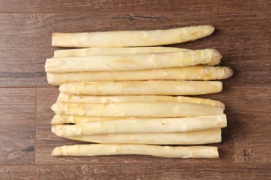 Ahşap masanın üstünde çiğ beyaz kuşkonmaz mızrakları.