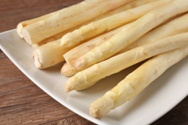 Ahşap masada çiğ beyaz kuşkonmaz mızrakları, yakın plan.