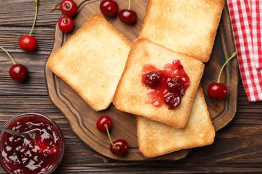 Lezzetli kiraz reçelli tostlar ve ahşap masada taze meyveler.