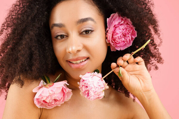 Beautiful Brazilian woman with peonies on pink background, closeup