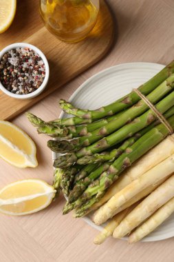 Ahşap masada farklı çiğ kuşkonmaz ve baharatlar var.