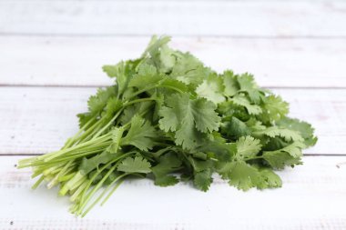 Beyaz ahşap masada taze aromatik kişniş, yakın plan.