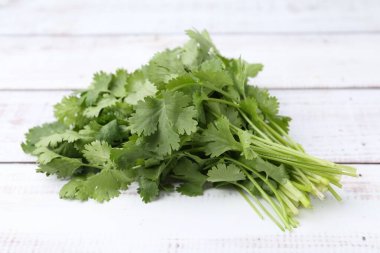 Beyaz ahşap masada taze aromatik kişniş, yakın plan.