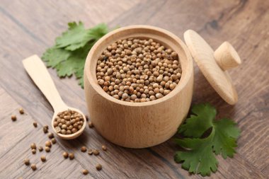 Taze kişniş ve kişniş tohumları ahşap masada, yakın plan.