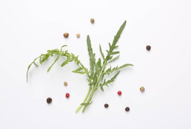 Taze yeşil roka yaprakları ve beyaz arka planda biberler, düz yatıyordu.