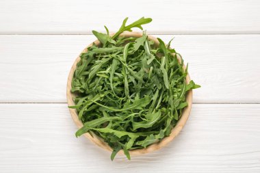 Taze yeşil roka yaprakları beyaz ahşap masada, üst tarafta.