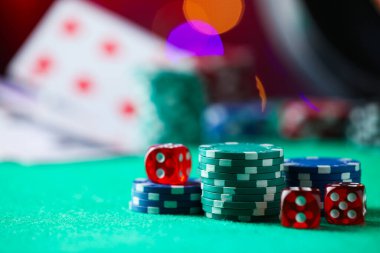 Kumarhane fişleri ve zarlar yeşil masada bulanık ışıklara karşı, yakın plan. Metin için boşluk