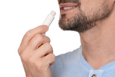 Gülümseyen adam dudaklarına merhem sürüyor. Beyaz arka planda, yakın plan.