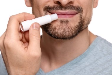 Beyaz arka planda dudaklarına dudak kremi süren adam, yakın plan.