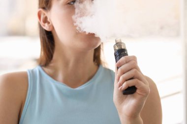 Dışarıda elektronik sigara içen genç bir kadın, yakın plan.