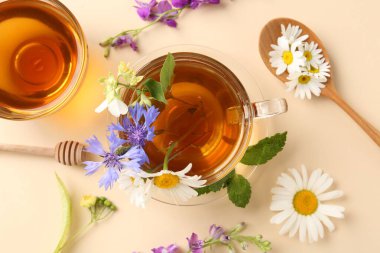 Cam fincanlarda aromatik bitki çayı, farklı çiçekler ve bej arka planda nane şekeri, düz uzanmış