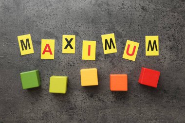 Sözcük maksimum ve renkli küpler gri masada, düz yatıyordu