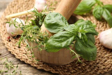 Kabuklu havan, farklı aromatik otlar ve baharatlar ahşap masada, yakın plan.