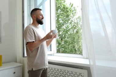 Uyum. Evinin penceresinin yanında bir bardak içkisi olan adam.