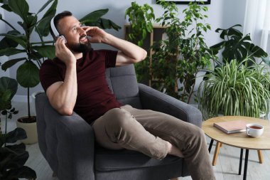 Uyum. Evde kulaklıkla müzik dinleyen bir adam.