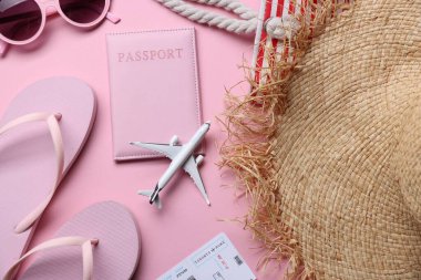 Uçak modeli, pasaport, uçuş bileti ve pembe arka plandaki aksesuarlar, düz konum.