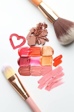 Beyaz arka planda farklı kozmetik ürünler ve makyaj fırçaları, düz yatış